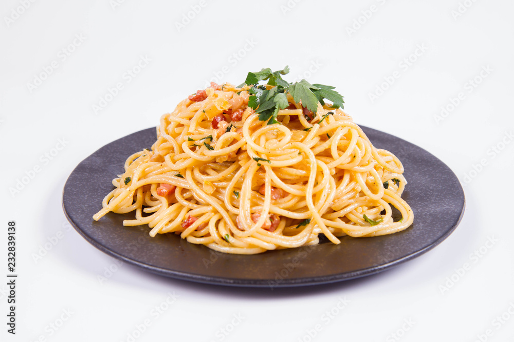 Spaghetti Carbonara with some parsley on a black plate on a white background