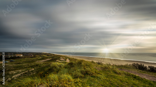 Coast in Denmark with sun shining through clouds (Long exposure)