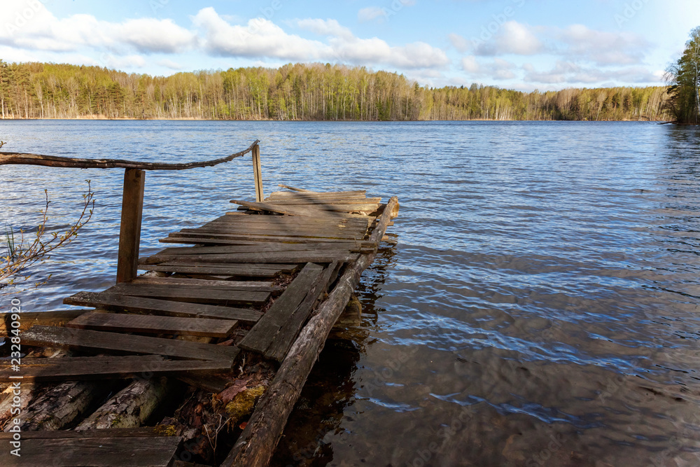Traditional Russian Finnish and Scandinavian view. Beautiful forest lake or river on sunny summer day and old rustic wooden dock or pier. Fishing bridge on morning lake. Fishing tourism relax concept Traditional Russian Finnish and Scandinavian view. Beautiful forest lake or river on sunny summer day and old rustic wooden dock or pier. Fishing bridge on morning lake. Fishing tourism relax concept