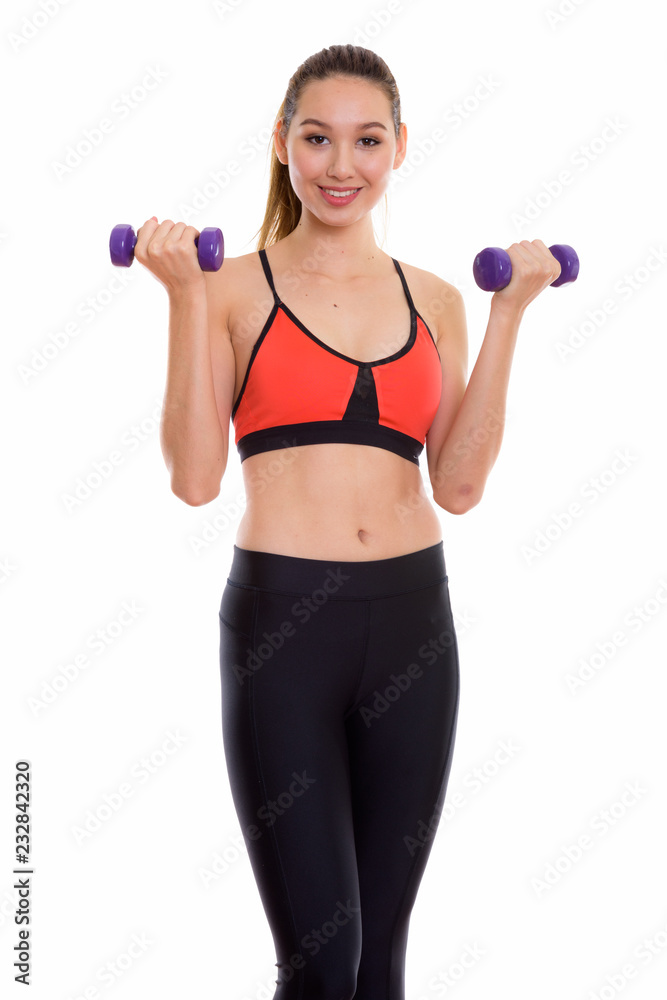 Studio shot of young happy beautiful Asian woman smiling while e Studio shot of young happy beautiful Asian woman smiling while e