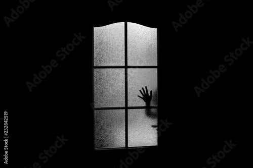 Dark silhouette of hand behind glass in supernatural light. Locked alone in room behind door on Halloween. Nightmare of kid with aliens, monsters and ghosts. Evil in home. Сhild inside haunted house. photo