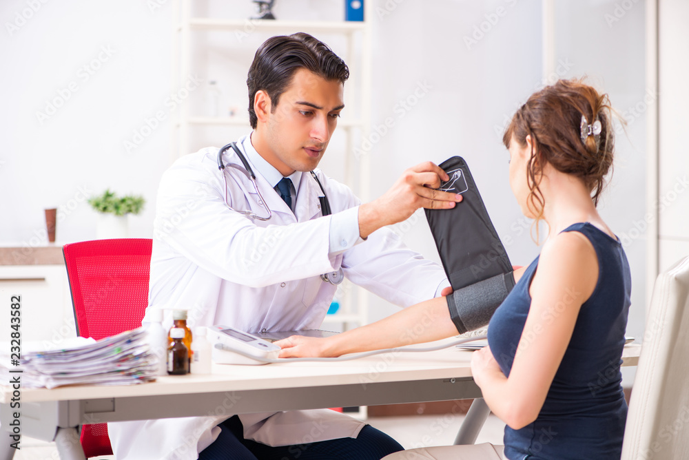 Young doctor checking woman's blood pressure Young doctor checking woman's blood pressure