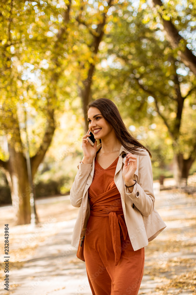Happy young woman using cell phone in autumn park Happy young woman using cell phone in autumn park