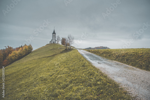Road on the hill and Church of St. Primus and Felician, Jamnik, Slovenia.
