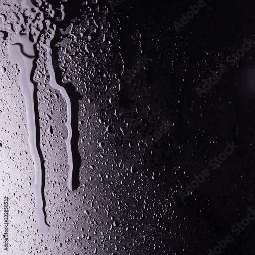 water drops on a black background with the reflection of light spots. flowing drop