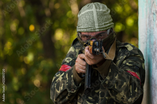 Front view of airsoft warrior in camouflage aiming his weapon forward