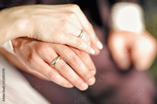 The bride and groom tenderly squeeze each other's palms. Wedding rings are visible