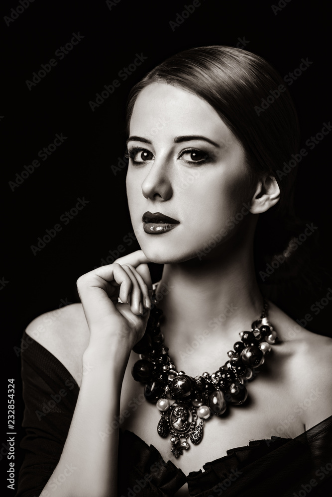 portrait of a style white woman in necklace on dark background. Image in white and black color style.