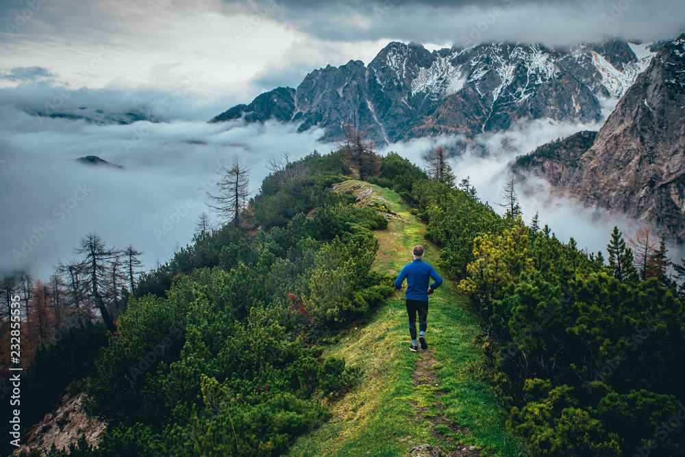 Tourist in blue jacket walking on green mountains ridge. Julian Alps, Slovenia. Vrsic Pass