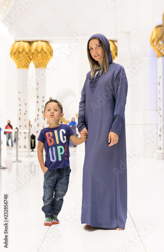 Woman with cute son dreaming  in Abu Dhabi wearing abaya, paranja in night time. Travelling.