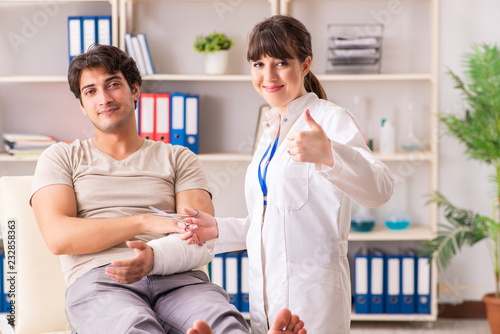 Young man with bandaged arm visiting female doctor traumatologis photo