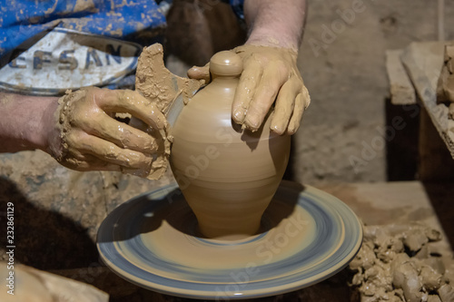 hands of potter creating a jar on circle