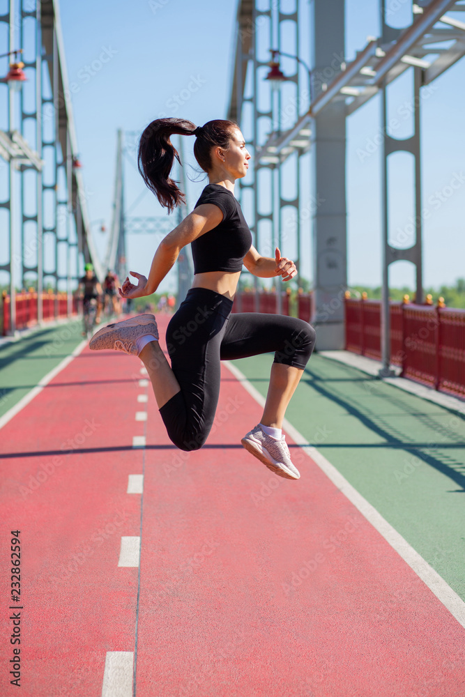 Young woman athlete in sport apparel jumping during the workout. Empty space
