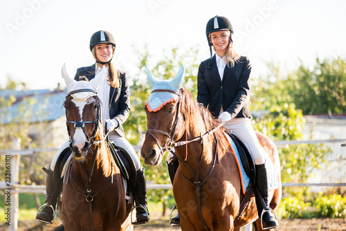 Two girls riding a horse on a farm. 