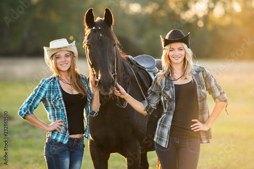 Two girls rider stands near a horse. Horse theme