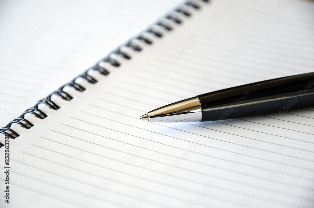 Representative pen laying on a blank note book . Close-up view Representative pen laying on a blank note book . Close-up view