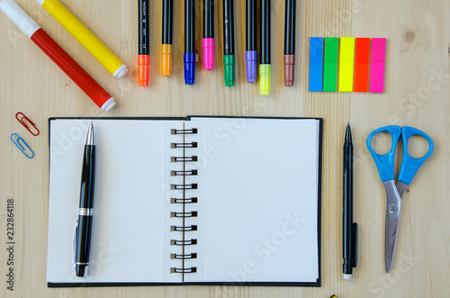 Office supplies laying on a wooden desk background.Top view. Pencils,scissors,markers,stickers,bookmarks,glasses