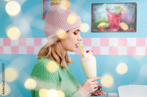 Beautiful young girl drinking vanilla milkshake in cafe