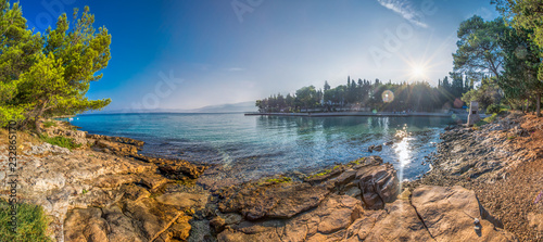 Pebble beach on Brac island with pine trees and turquoise clear ocean water, Supetar, Brac, Croatia
