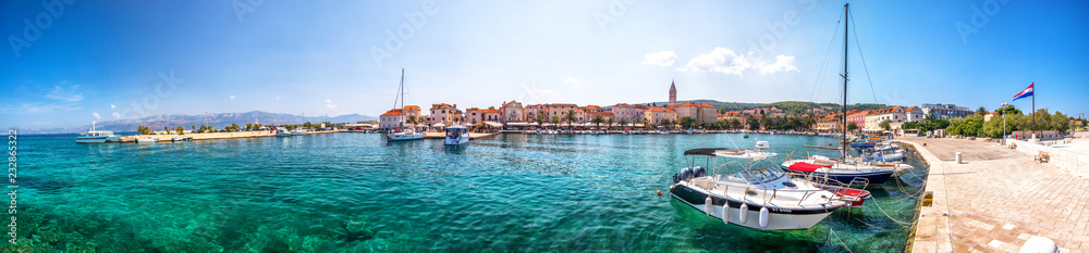 Seaside promenade and harbour in Supetar town on Brac island with palm trees and turquoise clear ocean water, Supetar, Brac, Croatia, Europe