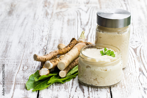 Tableau sur toile Spicy horseradish sauce in glass jar on wooden table