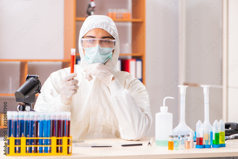 Young biochemist wearing protective suit working in the lab Young biochemist wearing protective suit working in the lab