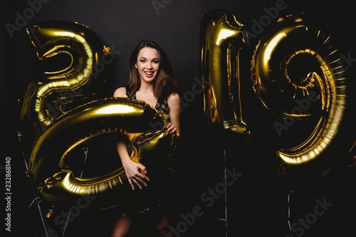New Year. Woman With Balloons Celebrating At Party. Portrait Of Beautiful Smiling Girl In Shiny Dress Throwing Confetti, Having Fun With Gold 2019 Balloons On Background. High Resolution.