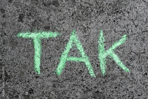 Słowo TAK napisane zieloną kredą na betonie. Dziecięcy napis