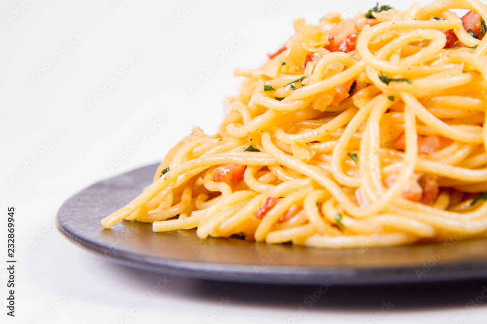 Spaghetti Carbonara with some parsley on a black plate on a white background Spaghetti Carbonara with some parsley on a black plate on a white background