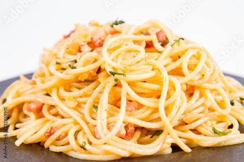 Spaghetti Carbonara with some parsley on a black plate on a white background