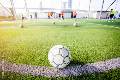 ootball on green artificial turf with blurry of soccer players are training. © Koonsiri