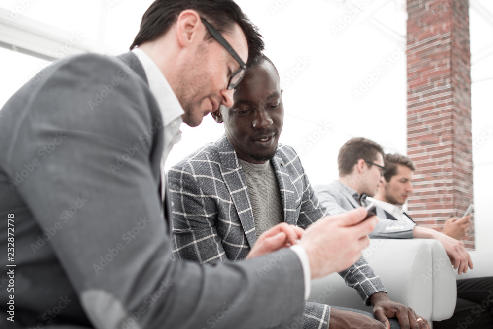 Fototapeta premium two employees look and read on the smartphone screen.