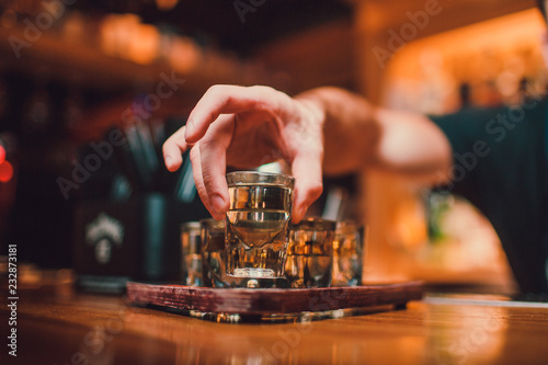 Bartender is pouring tequila into glass against the background of the bar. photo