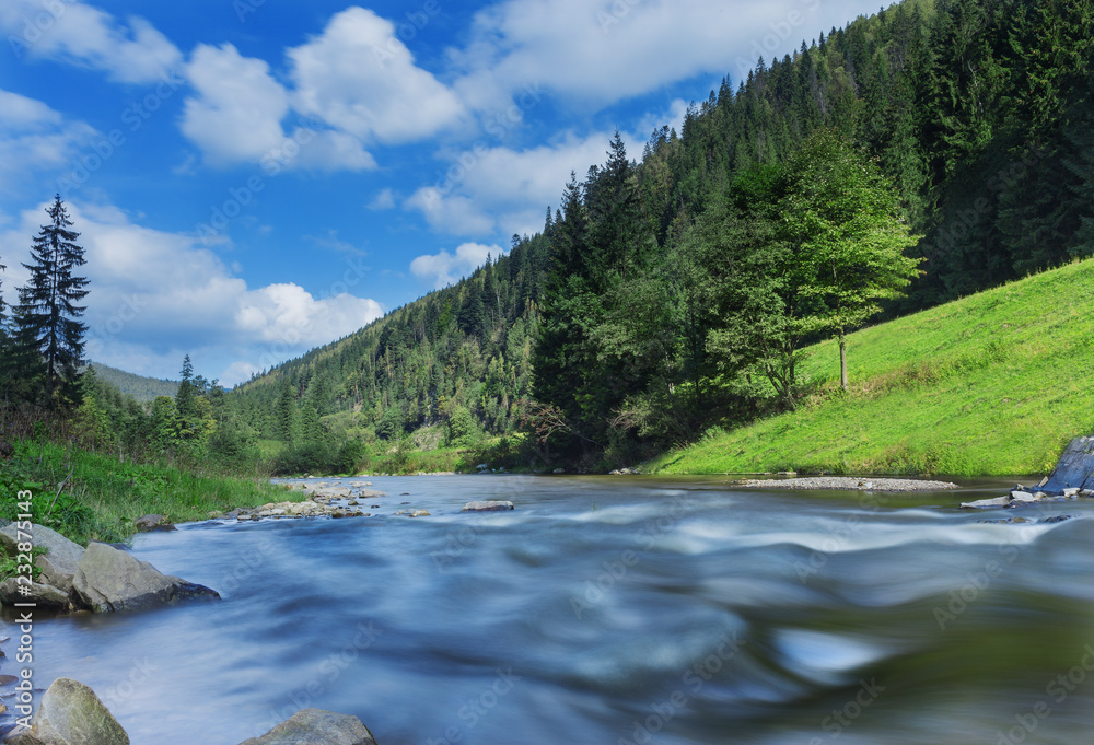 River in mountains with rocks, green grass on riverside. Mountain landscape, beautiful sky, clouds. Idea for outdoor activities, travel . River in mountains with rocks, green grass on riverside. Mountain landscape, beautiful sky, clouds. Idea for outdoor activities, travel .