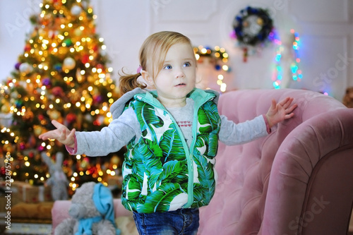Ребенок ждет чуда в Новый год. С новым годом! Счастливого Рождества! Новогодняя елка с рождественскими игрушками. Девочка на диване.
