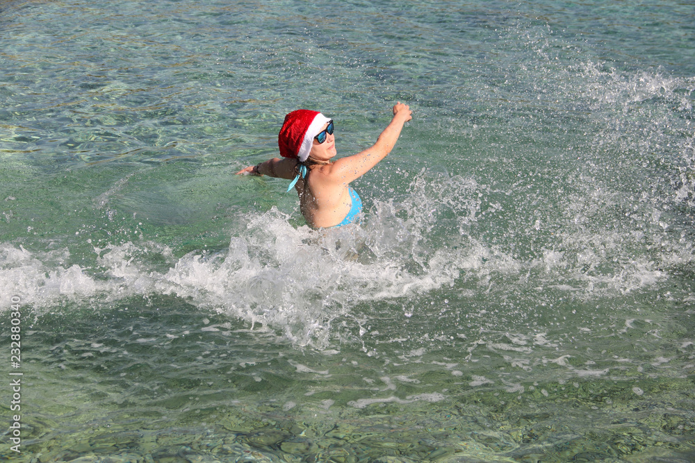 Woman in Santa hat splashing in sea