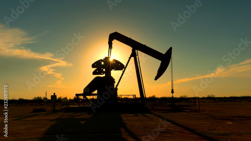 Industrial jack pump platform pumping crude oil over sunset sun