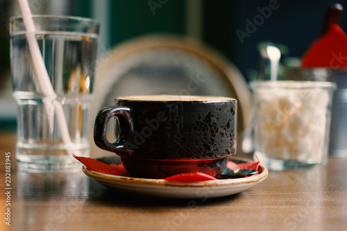 Side view of cappuccino on table with shugar bowl and glass of water