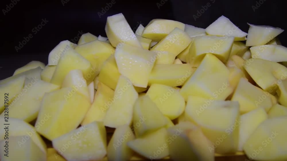 A lot of potatoes on table and on a cutting board. Potatoes, sliced on a cutting board. A lot of potatoes on table and on a cutting board. Potatoes, sliced on a cutting board.