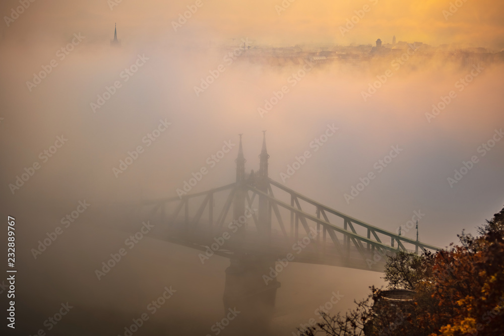 Budapest, Hungary - Mysterious foggy sunrise with Liberty Bridge (Szabadsag hid) and hazy skyline of Budapest at autumn morning