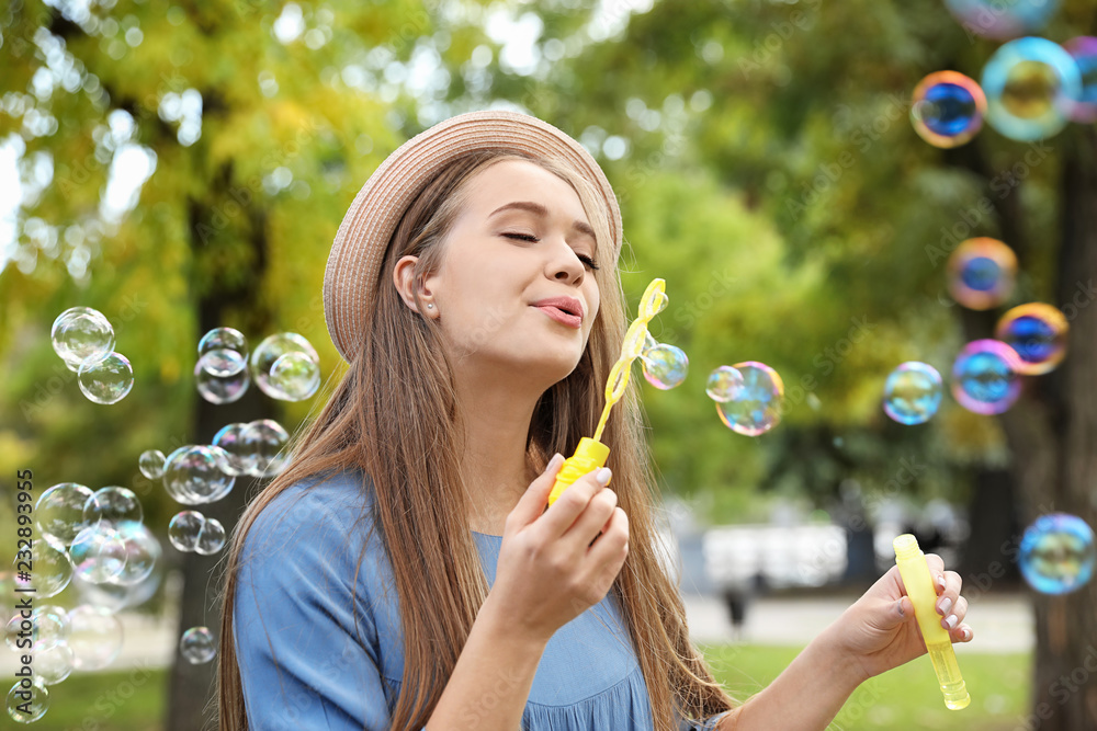 Young woman blowing soap bubbles in park