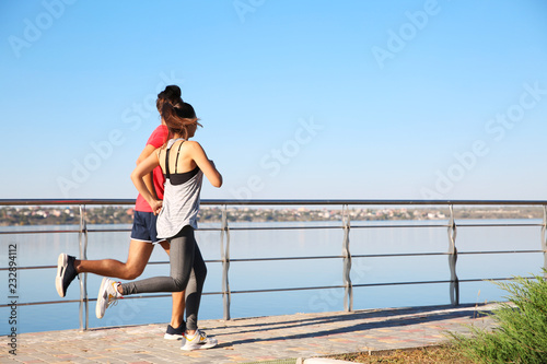 Sporty couple running outdoors on sunny morning © New Africa