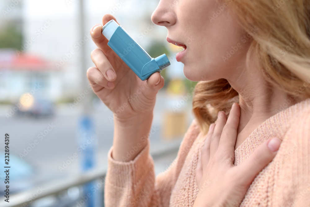 Woman using asthma inhaler outdoors, closeup. Health care Woman using asthma inhaler outdoors, closeup. Health care