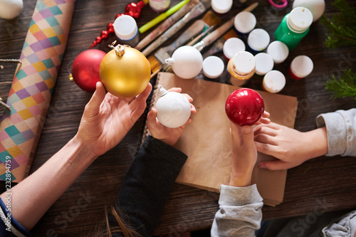 High angle close up of kids holding Christmas baubles over wooden table in crafting class, copy space