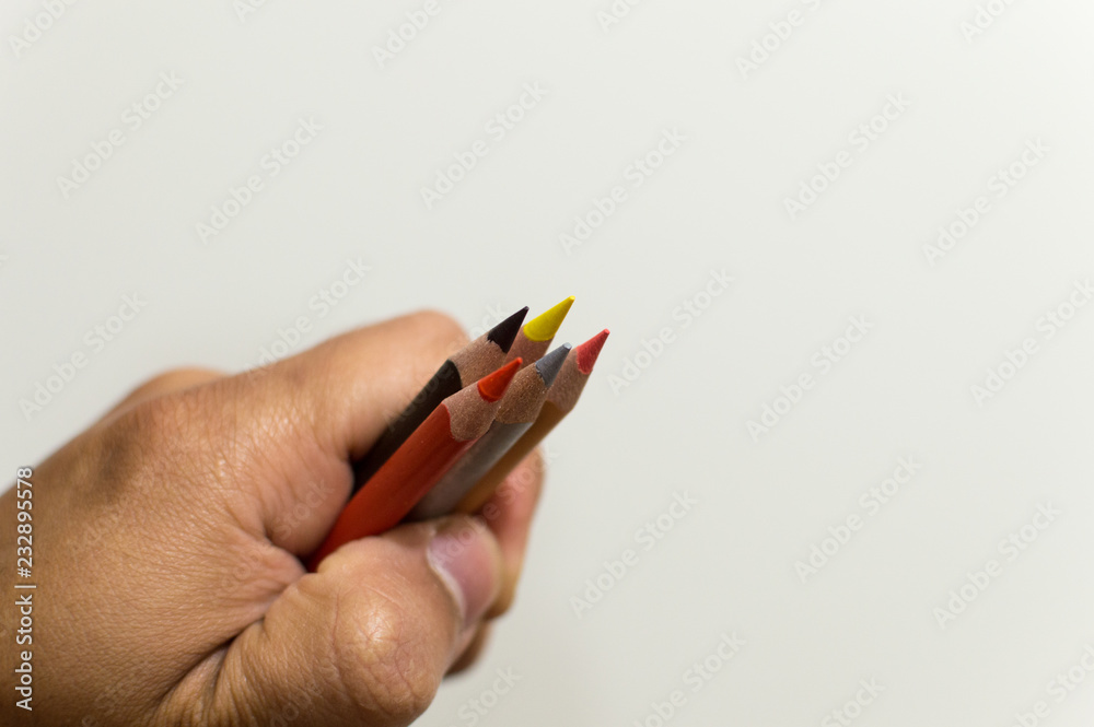 Hand holding color pencils on white background