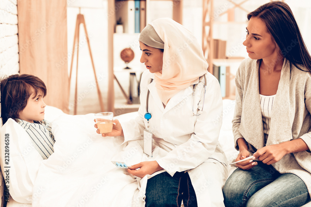 Fototapeta premium Arabic Doctor Give Medicine to Sick Boy Lying Bed