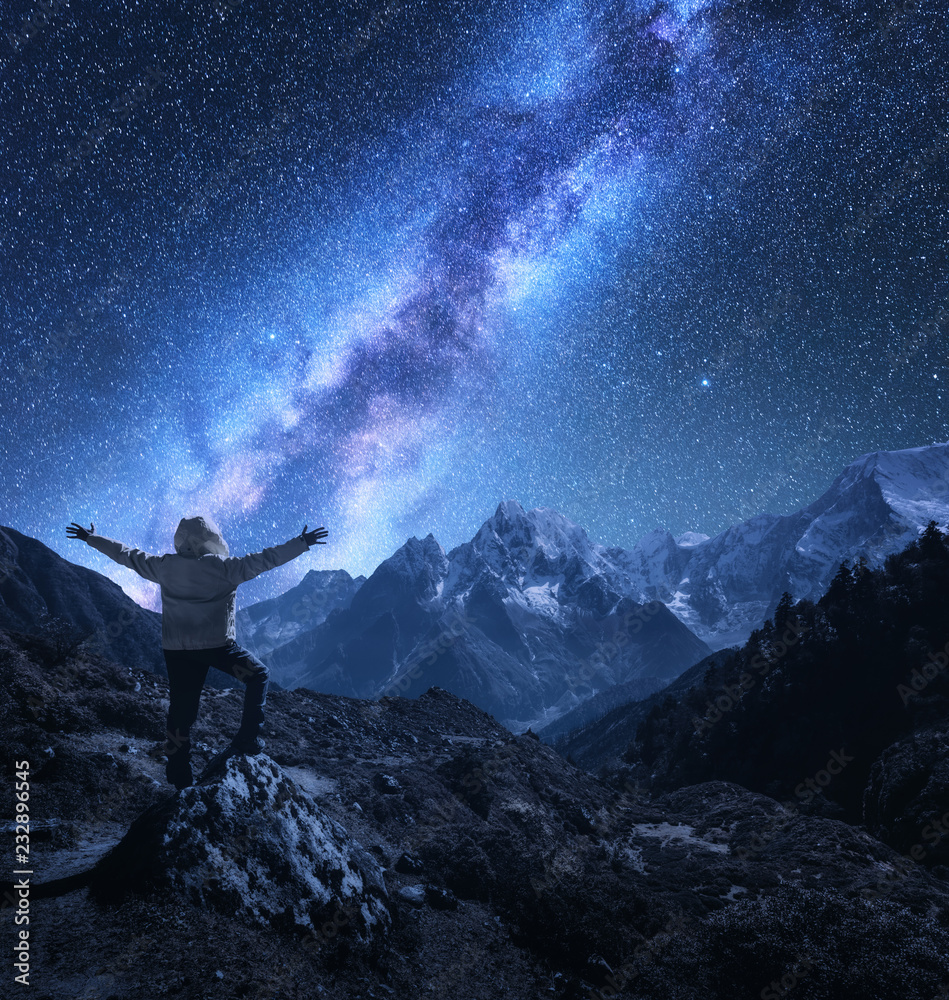 Silhouette of a standing man with raised up arms on the stone, mountains and starry sky with Milky Way at night in Nepal. Sky with stars. Travel. landscape with mountain ridge and milky way. Space Silhouette of a standing man with raised up arms on the stone, mountains and starry sky with Milky Way at night in Nepal. Sky with stars. Travel. landscape with mountain ridge and milky way. Space
