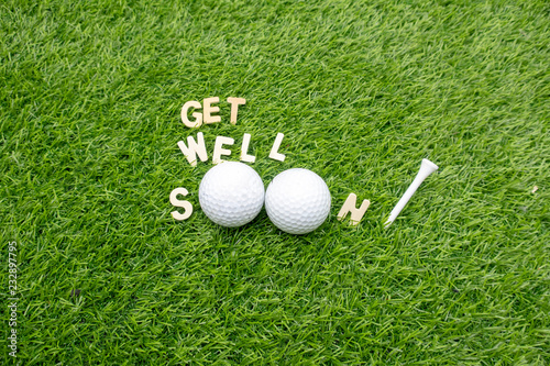 Get well soon word with golf ball and tee on green grass to golfer