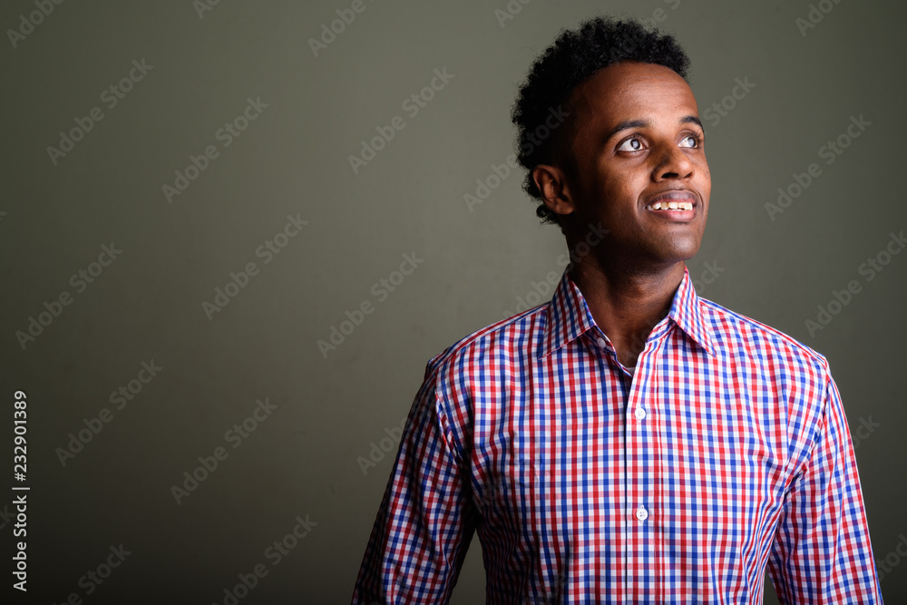 Obraz premium Young handsome African businessman against colored background
