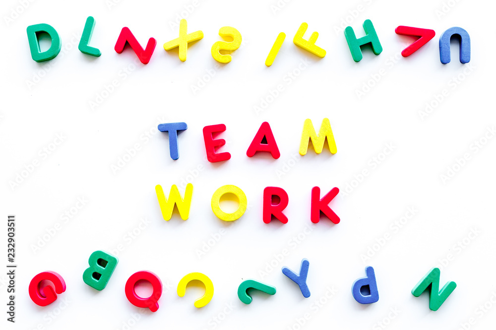 Fototapeta premium Teamwork training concept. Text teamwork lined with colored letters near toy letters on white background top view space for text